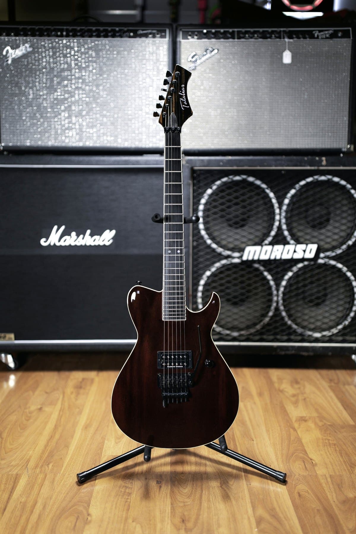 A handmade Tatalias carved-top in deep red on a stand in front of the shop's Marshall wall