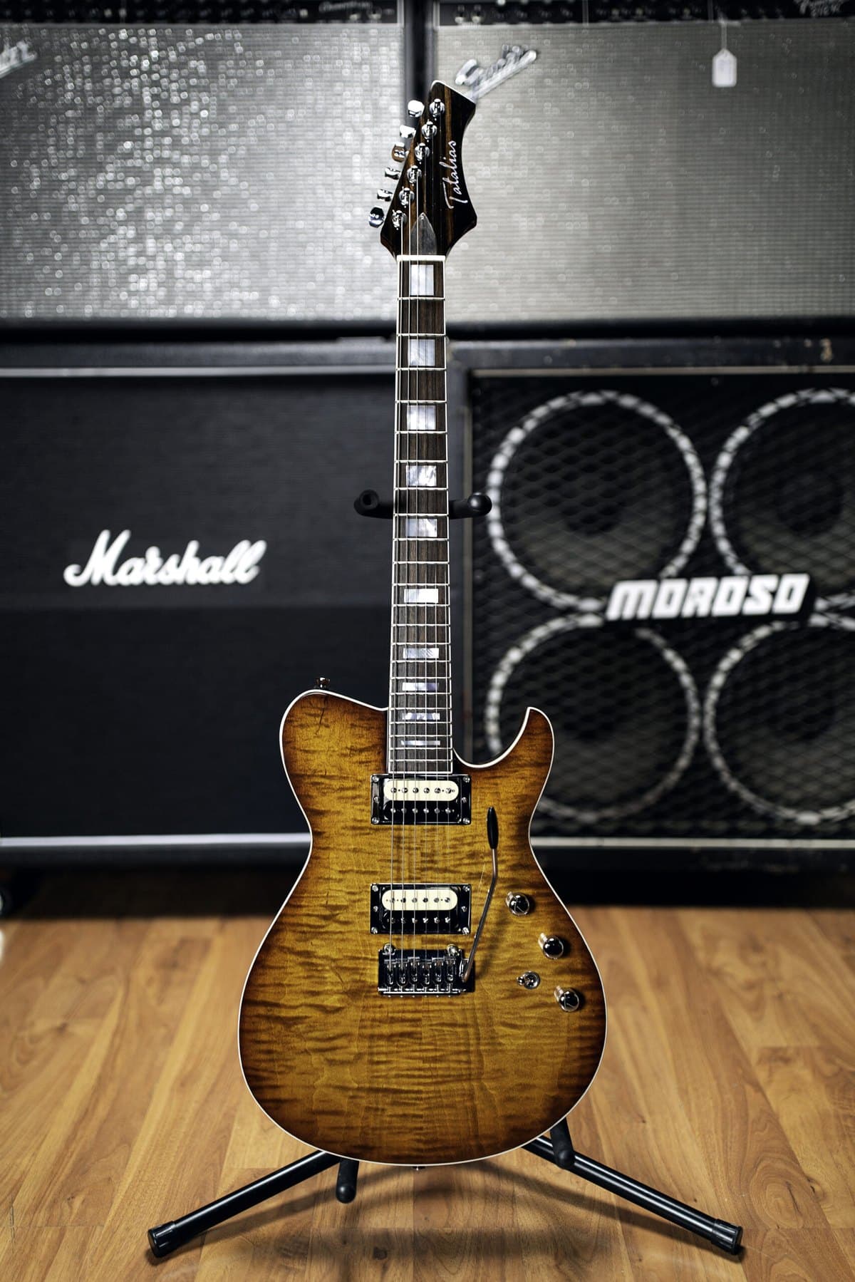 A handmade Tatalias flame-maple carved-top in a burst finish in front of the amp wall